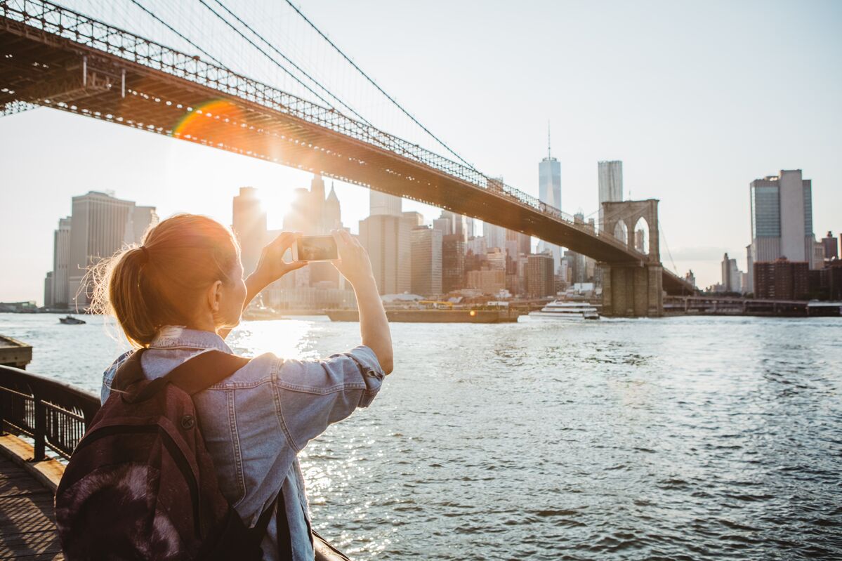 Person next to bridge taking photo with a smartphone