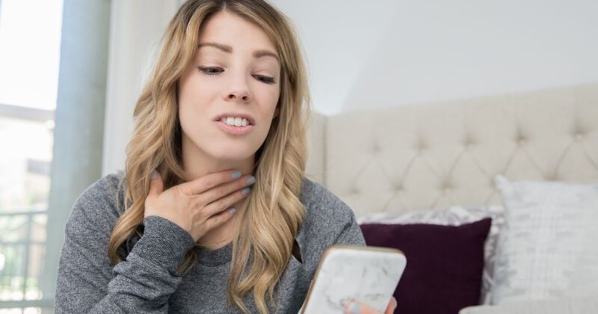 Person on smartphone gesturing toward neck