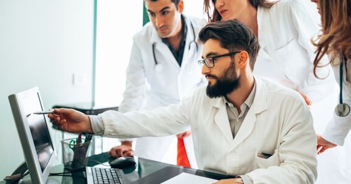 Doctor pointing at computer screen in front of colleagues