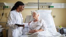 Healthcare provider talking to patient in a bed