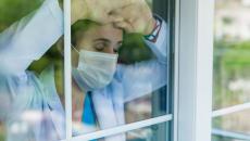 Medical worker leans against window