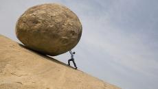 Person rolling a boulder uphill