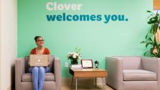 Lobby with seated person and the sign "Clover Health welcomes you" on the wall