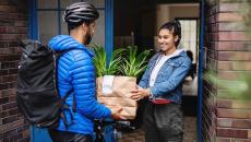 Food delivery person handing a bag to a person standing in their doorway