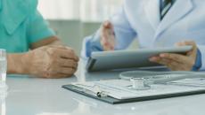 Doctor reviewing medical records on a tablet with a patient