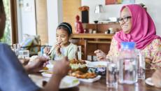 People sitting around a dining room table eating a meal