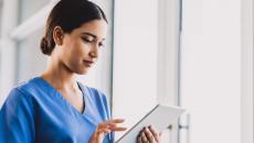 Nurse standing in a hallway holding a tablet