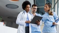 Three healthcare providers standing next to each other and looking at a tablet