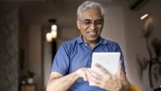 An elderly using a digital tablet at home