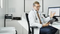 Healthcare provider sitting at a desk while talking to someone on the computer