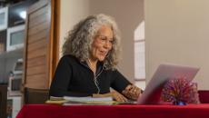 Person sitting at a dining room table looking at a computer