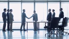 Company officials shake hands to close a business deal