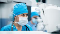 Surgeon standing in front of a computer dressed in surgical gear