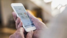 A person holding a phone showing a blood pressure reading