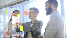 People standing in a room looking at Post-its on a wall