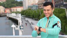 Person wearing a green sweater standing outside looking at a watch