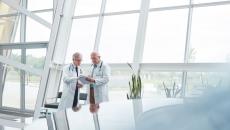 Two healthcare providers standing in a room in front of large windows