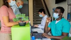 Healthcare providers sitting at a table with two people standing up on the other side