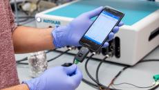 Penn researcher holding a smartphone as it uses the RAPID test to detect COVID-19