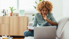 Individual sitting on a couch and looking at a computer