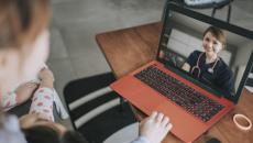 Two people sitting down while looking at a computer with a healthcare provider on the screen