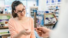 Person handing a piece of paper to a pharmacist