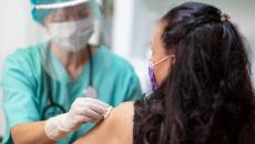 Healthcare professional in a mask swabs patient arm with cotton before administering a vaccine