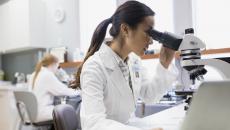 Health care practitioner looking through a microscope