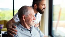 adult caregiver and person look out a window