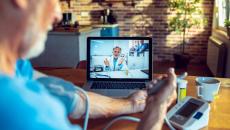 Patient taking a blood pressure reading while video-calling with a doctor.