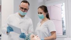 Dentist and his assistant using tablet in the process of treating teeth of patient