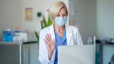 A doctor wearing a mask talking to a patient via telehealth