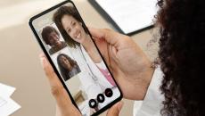 A close up of a woman holding a smartphone during an eVisit telehealth consultation