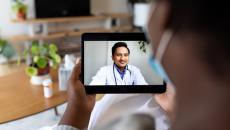 Person holding up a tablet with a telehealth provider on the screen