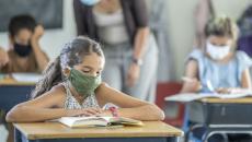 A student in school reading while wearing a mask