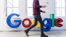 A man walking past a Google sign