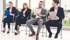 Four seated people fill out forms on clipboards