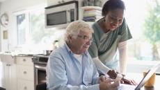 Home healthcare professional and client discuss instructions on a pill bottle