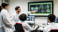 A group of doctors discussing a patient's test results on a large monitor in an office.