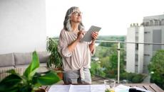 older woman on her apartment balcony with a tablet