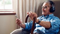 An older man in his home listening to music on his smartphone