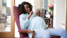 pregnant woman sitting in an armchair using a tablet