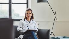 Therapist sitting on a couch with a clipboard