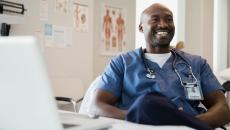 Healthcare provider sitting at a desk while wearing scrubs