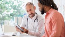 Healthcare provider sitting next to a person while both are looking at a tablet