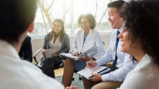 Five business people sitting on chairs in a circle 