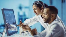 Two scientists sitting at a computer looking at the screen