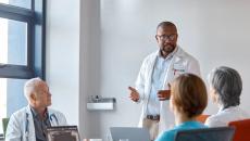 Healthcare provider standing in front of three other people in a meeting room