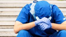 Healthcare provider sitting with their head in their hands