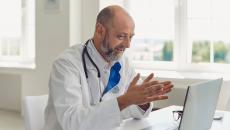 Healthcare provider sitting at a desk and talking to someone on a computer